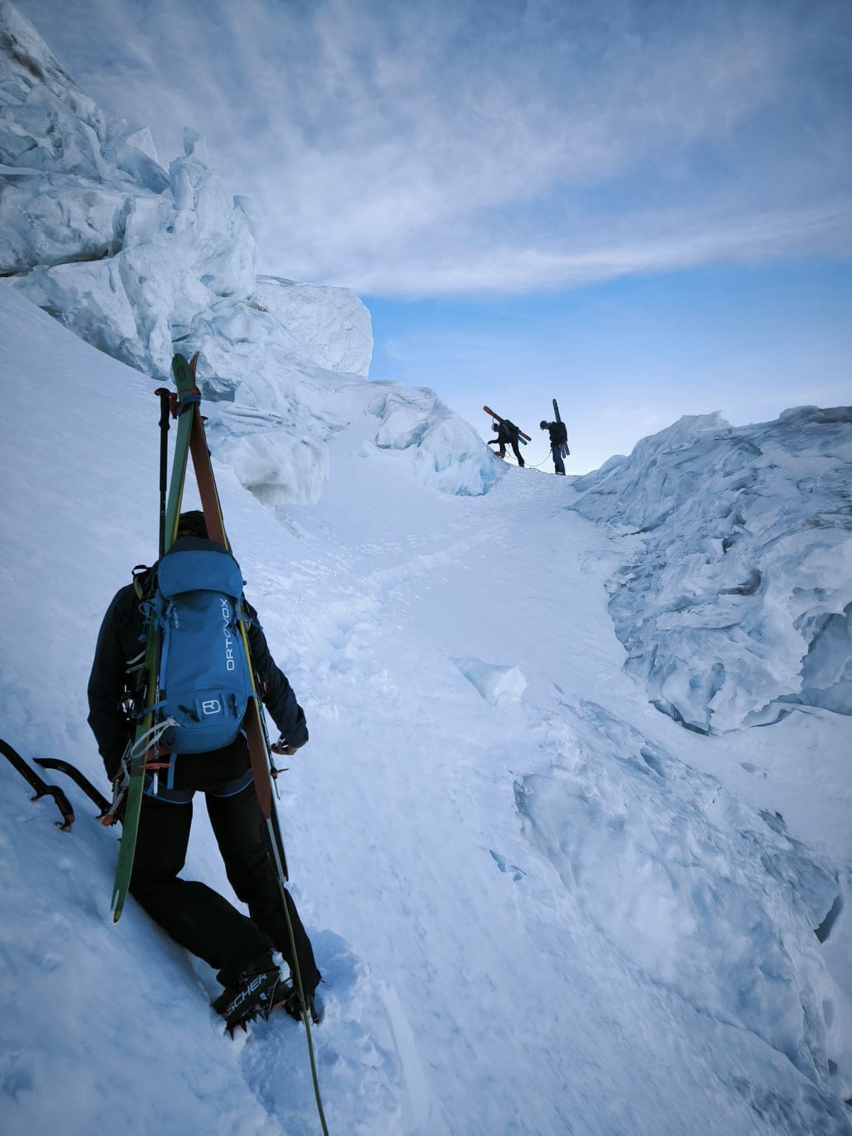 Alpinisti con gli sci sullo zaino salgono tra i seracchi di un ghiacciaio