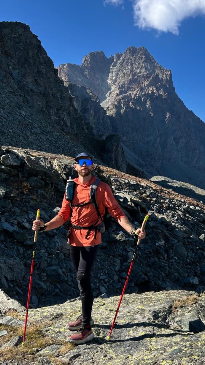 Marcello con i bastoncini da trekking davanti a una cima rocciosa